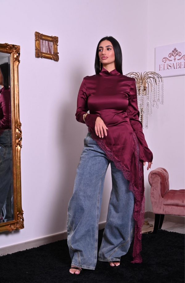 Blusa in satin borgogna con pizzo e taglio asimmetrico, elegante e raffinata.