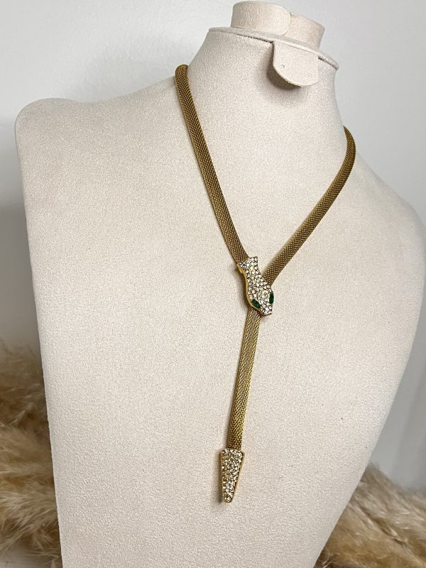 Un serpente dorato che avvolge il décolleté con eleganza ipnotica. Brilla di cristalli e scivola lungo il corpo con fascino irresistibile.