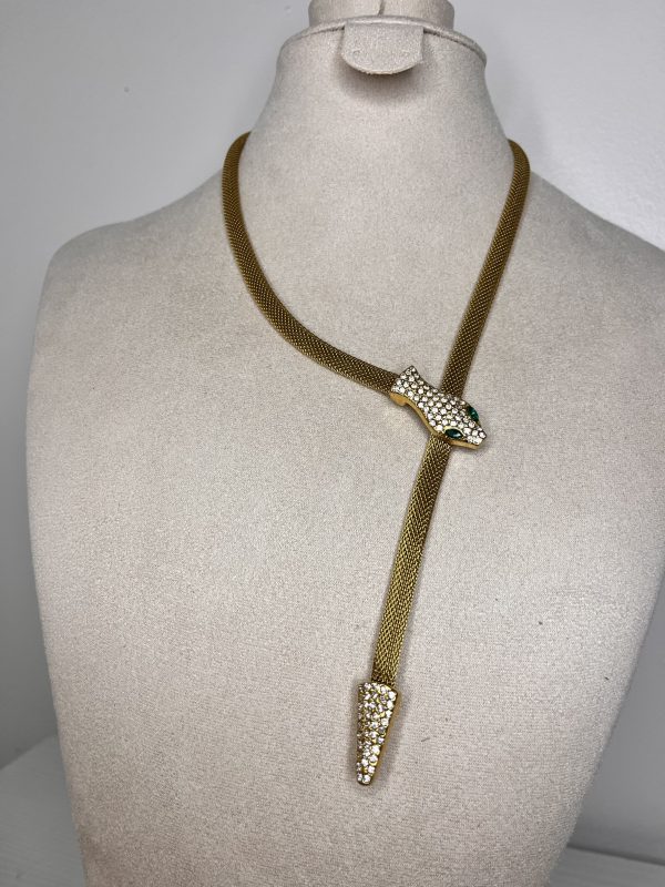 Un serpente dorato che avvolge il décolleté con eleganza ipnotica. Brilla di cristalli e scivola lungo il corpo con fascino irresistibile.