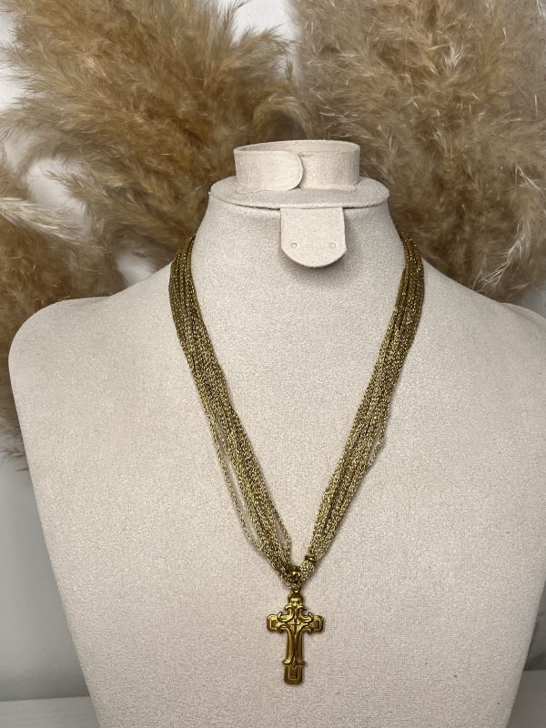 Collana a più fili dorati con ciondolo a croce decorata, elegante e dal carattere deciso.