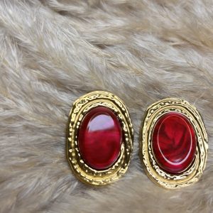 Orecchini ovali con cabochon rosso intenso e cornice dorata martellata, dal carattere elegante e deciso.