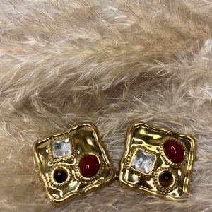 Orecchini dorati dal design artistico con gemme rosse, nere e cristallo trasparente. Un mix di forme e colori che cattura lo sguardo.