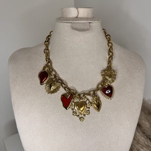 Collana a catena dorata con ciondoli a forma di cuore in smalto rosso e dettagli spirituali, elegante e simbolica.