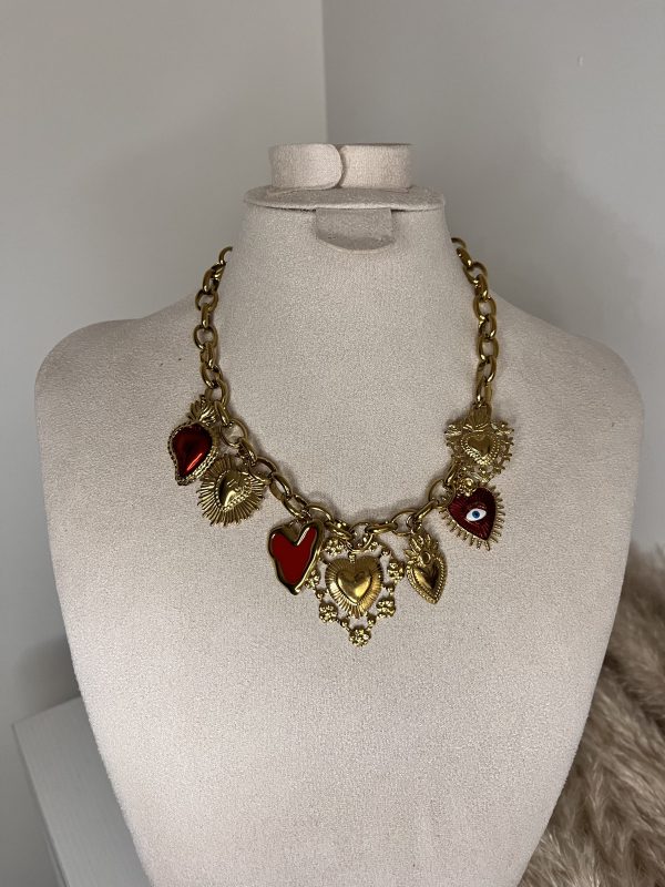 Collana a catena dorata con ciondoli a forma di cuore in smalto rosso e dettagli spirituali, elegante e simbolica.