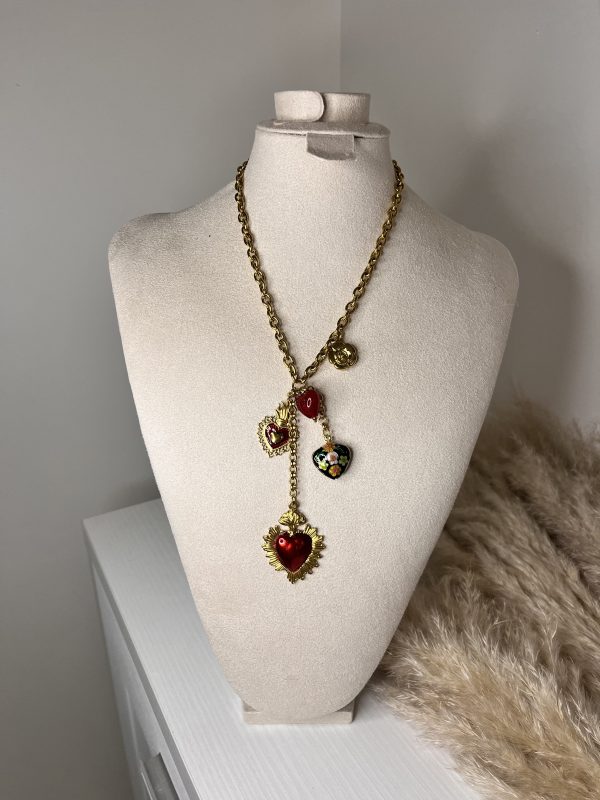 Collana dorata con pendenti a cuore smaltati e dettagli floreali, disposti a cascata per un effetto elegante e romantico.