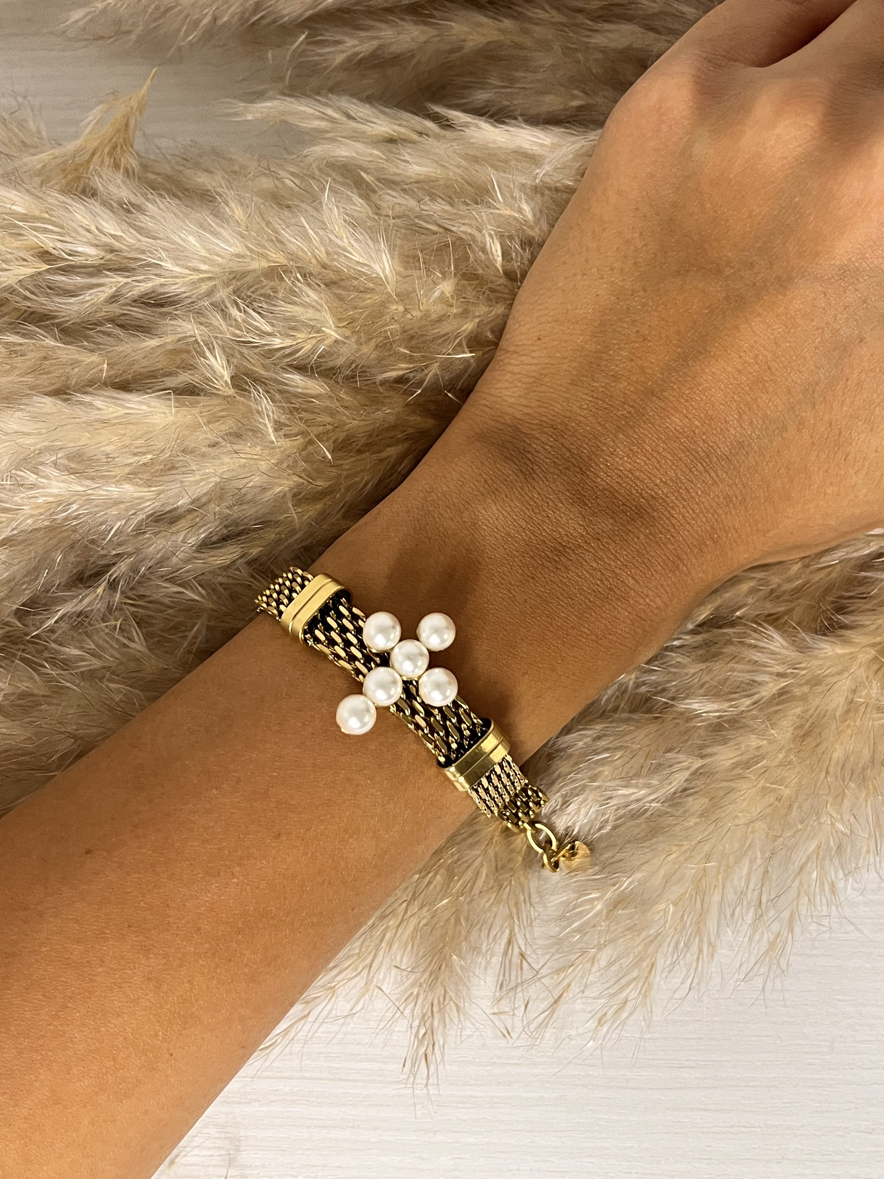 Eleganza preziosa! Questo bracciale Elisabeth Fashion unisce una fascia lavorata color oro con un affascinante cluster di perle luminose disposte a forma di incrocio. Un accessorio chic e femminile, perfetto per un tocco Diva che completa ogni look con grazia.