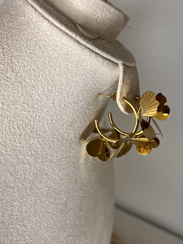 Un bouquet di stile! Questi orecchini Elisabeth Fashion sono a cerchio, impreziositi da fiori in metallo dorato lucido con una texture elegante. Un accessorio artistico e glamour, perfetto per un look Diva che ama osare con un tocco cool e originale.
