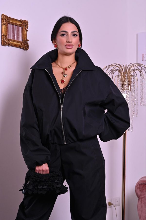 Tuta nera con zip, colletto maxi e fondo jogger a caviglia, dallo stile moderno e chic.
