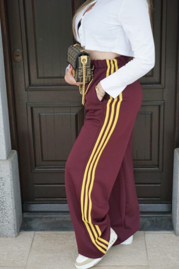 Pantaloni granata intenso a gamba larga con bande laterali gialle. Comodi, moderni e dal forte impatto visivo: perfetti per look sporty-street di carattere.