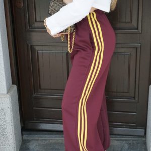 Pantaloni granata intenso a gamba larga con bande laterali gialle. Comodi, moderni e dal forte impatto visivo: perfetti per look sporty-street di carattere.