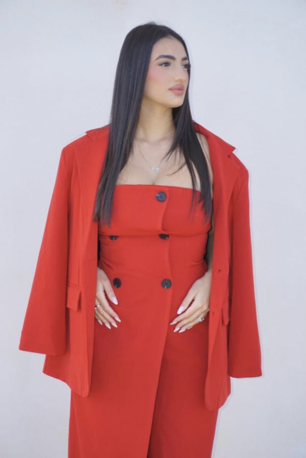 Tuta elegante rossa con bottoni frontali, abbinata a giacca oversize coordinata: un completo sofisticato e di carattere, perfetto per occasioni speciali.