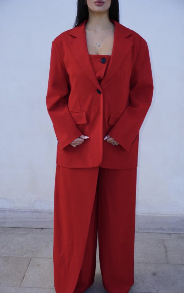 Tuta elegante rossa con bottoni frontali, abbinata a giacca oversize coordinata: un completo sofisticato e di carattere, perfetto per occasioni speciali.