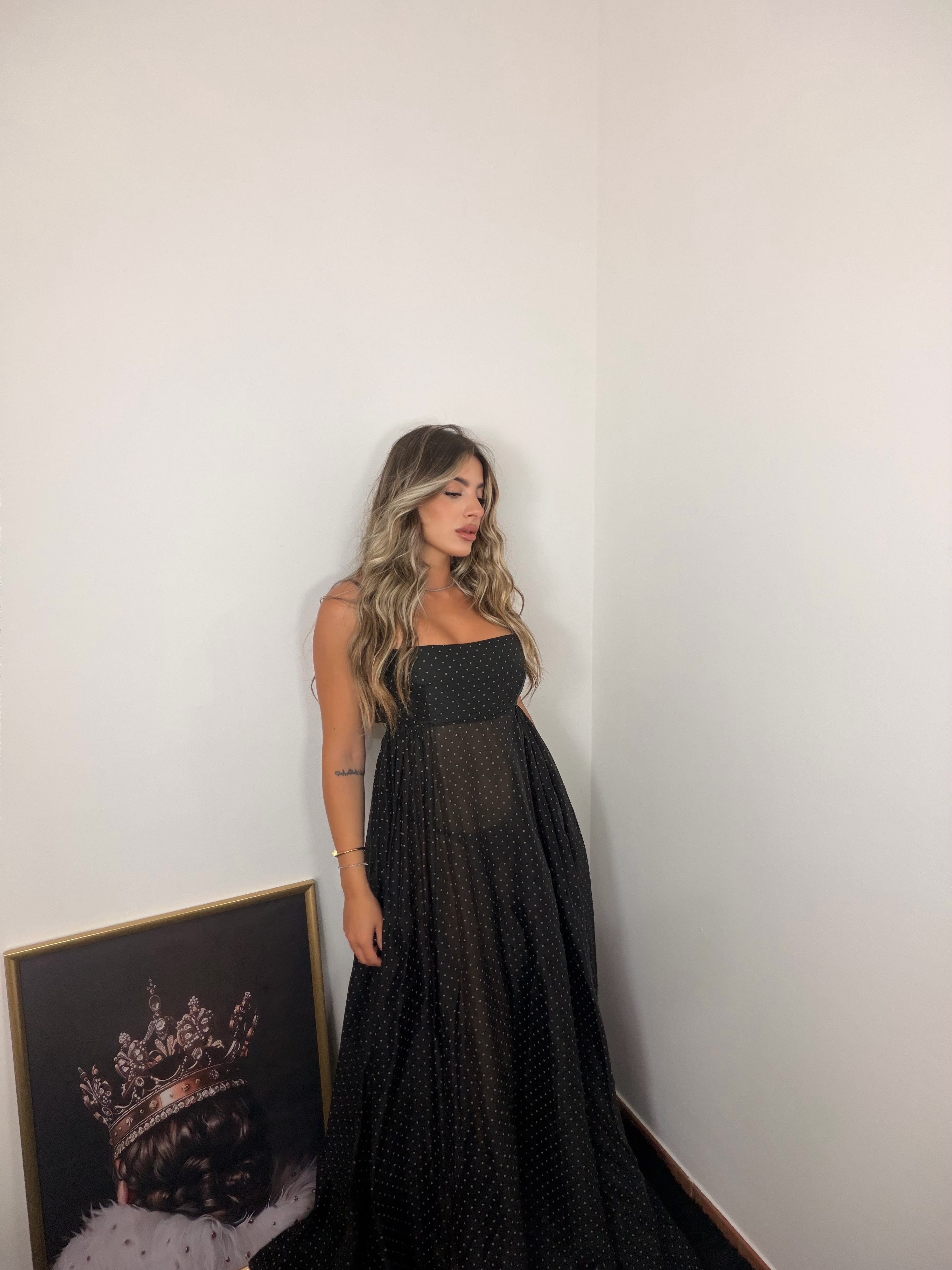 Abito lungo nero a pois con scollo a fascia e tessuto leggero. Perfetto per eventi, serate eleganti e occasioni speciali.